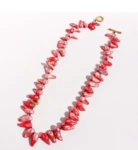Vue de détail rapprochée d'un collier de perles baroques rouges avec fermoir OT doré.