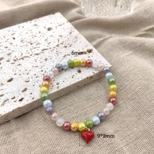 Detailopname van kleurrijke kralenarmband, levendige kralen met schattige rode hartvormige hanger.