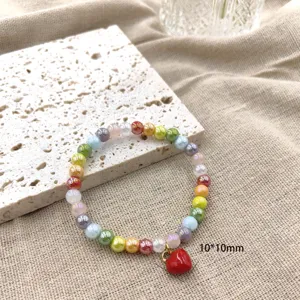 Close-up detail van kleurrijke dopamine kristal kralenarmband met rode hart hanger.