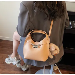 Detailed shot of women's casual leather bucket bag with metal lock and cute plush charm.