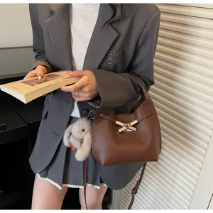 Brown leather bucket bag detail view with metal twist lock, stylish daily commuting accessory.