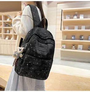 Vista dettagliata dello zaino nero con stampa di stelle, ciondolo orsetto e grande spazio.