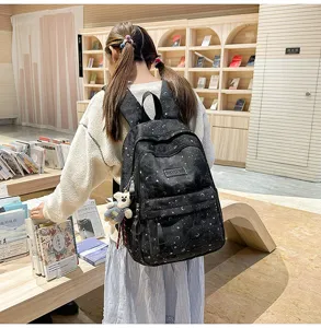 Vista dettagliata dello zaino scolastico nero con stampa di stelle, tasche frontali e ciondolo.
