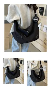Detailed view of large capacity black canvas shoulder bag with round pouch and adjustable strap.