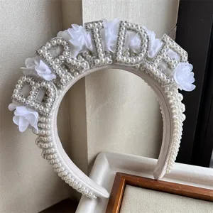 Λεπτομέρεια νυφικής στέκας BRIDE λευκά μαργαριτάρια, λαμπερά στρας και υφασμάτινα λουλούδια.
