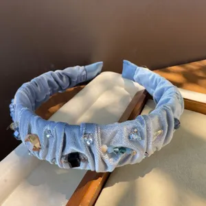 Elegante diadema de terciopelo azul claro con cristales, detalle de joyería retro.