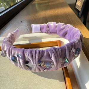 Detalle de diadema de terciopelo morado con pedrería y cristales que muestra abalorios hechos a mano.