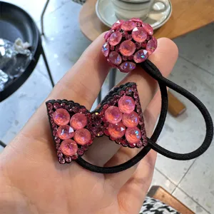 Close-up of sparkling pink rhinestone bow and ball hair tie, elegant crystal hair accessory.