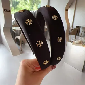 Black padded headband with gold cross studs, elegant wide hair hoop fashion accessory for women.