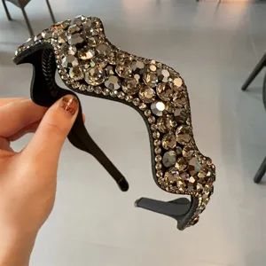 Nahaufnahme eines luxuriösen, gewellten Strass-Haarreifs mit funkelnden Kristallen auf schwarzer Basis.