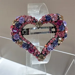 Vue détaillée de la pince à cheveux cœur en strass étincelants avec des cristaux roses et violets.