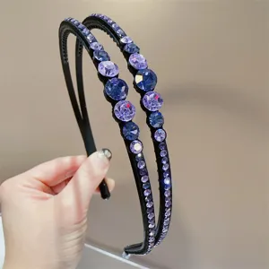 Gedetailleerd overzicht van een dubbelstrengse zwarte haarband met paarse strass-steentjes.