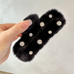 Close-up detail of a black furry claw clip with sparkling rhinestones for winter hair styling.