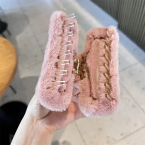 Close-up of a stylish pink furry square hair claw clip, soft plush texture, clear teeth.