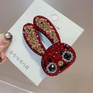 Detalle de horquilla de conejo con diamantes de imitación, diseño brillante en tarjeta blanca.