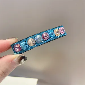 Close-up detail van een fonkelende strass haarspeld met kleurrijke kristallen en blauwe accenten.