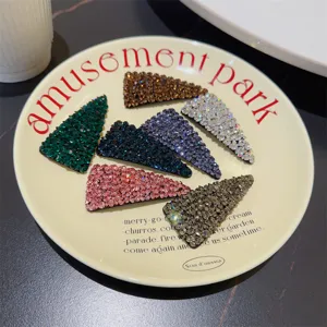 Vue détaillée de plusieurs pinces à cheveux triangulaires en strass colorés sur une assiette.