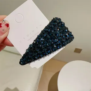 Gros plan sur la barrette à cheveux triangulaire en strass bleu foncé avec cristaux brillants.