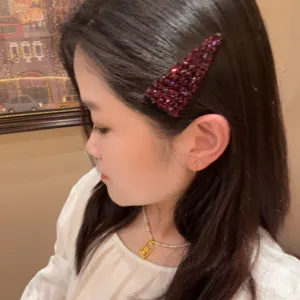 Vue detaillee de la pince a cheveux triangle strass, accessoire barrette cristaux rouges femme.