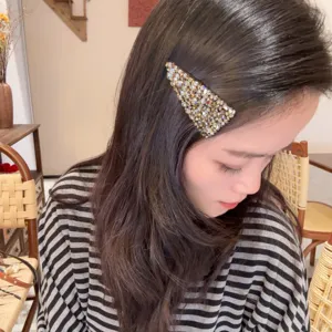 Gros plan d'une pince à cheveux triangulaire en strass étincelant, superbe détail élégant.