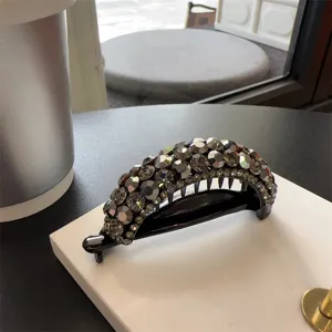 Gros plan d'une pince à cheveux banane en strass étincelant, design noir élégant.