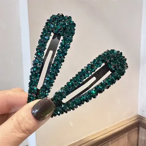 Nahaufnahme Detail der funkelnden dunkelgrünen Strass Haarnadeln mit glänzender Kristallstruktur.