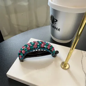 Gros plan détaillé d'une pince à cheveux banane en strass étincelante aux décors colorés.
