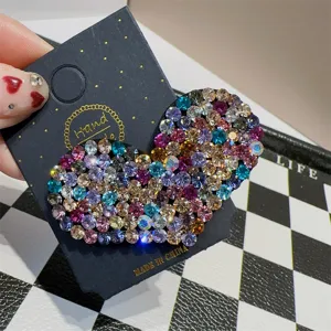 Detaillierte Nahaufnahme einer funkelnden bunten Strass-Herz-Haarspange auf einer Karte.