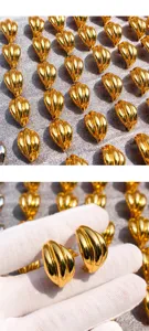Gold geometric wave metal earrings detail, featuring polished curved lines and glossy finish.