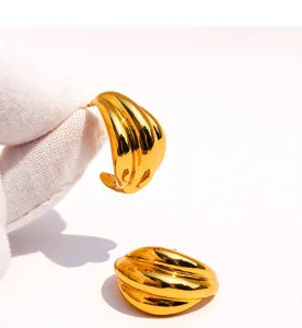 Detailed shot of chunky gold wave geometric earrings, showing unique streamline metal texture.