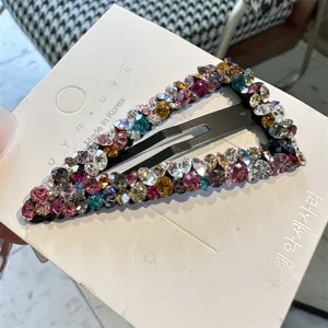Detailansicht einer geometrischen Haarklammer besetzt mit bunten funkelnden Kristallen auf Karte.