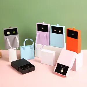 Scatole portagioie a cassetto colorate con manici in nastro e inserti in velluto per anelli.