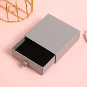 Primo piano dettaglio del portagioie a cassetto grigio con fodera in velluto.