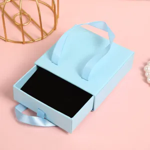 Dettaglio del portagioie a cassetto azzurro chiaro con nastro e interno in velluto.