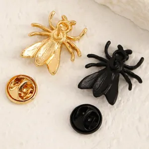 Primo piano dettaglio di spilla insetto in metallo creativo, accessorio spilla oro e nero.