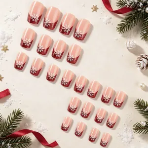 Detail vankerstkunstnagels, korte vierkante vorm met rode glitter en witte sneeuwvlokken.