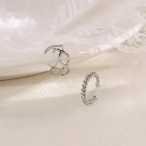 Detailed shot of silver non-pierced ear cuffs featuring geometric wave and twisted rope designs.