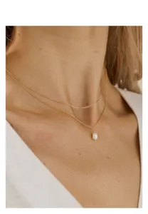 Vue détaillée en gros plan du elegante collar de doble cadena dorada con perla.