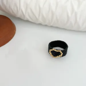 Anello cuore di perline nere e oro fatte a mano, stile dolce e cool, vista di dettaglio.