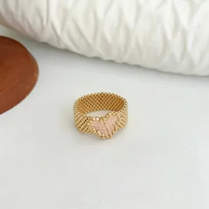 Primo piano di un elegante anello di perline fatto a mano con cuore rosa dorato.