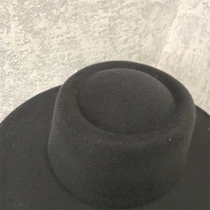 Black felt flat top hat detail view, showcasing the classic wide brim texture and woolen fabric.