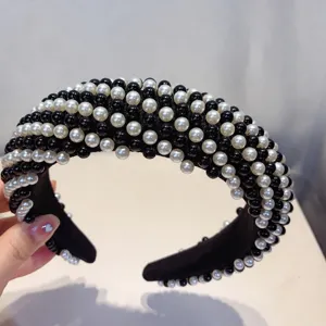 Diadema ancha de esponja negra adornada con perlas negras y blancas alternas para estilo.