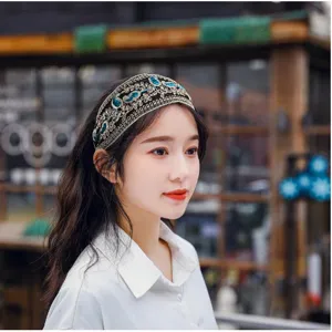 Detailed view of luxury vintage embroidered headband with gold thread and blue crystal decorations.