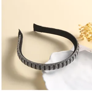 Close-up of sparkling pearl rhinestone headband detail on white dish, elegant hair accessory