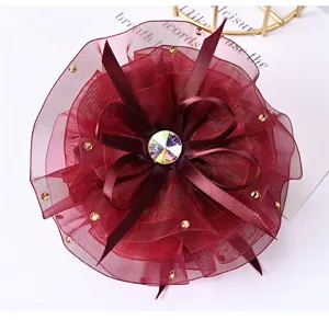 Detailed close-up of a wine red mesh flower hair clip with rhinestones and ribbon layers.