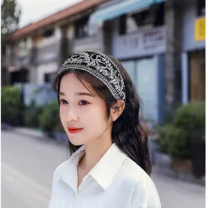 Close-up view of a chic black headband featuring elegant silver embroidery worn outdoors.