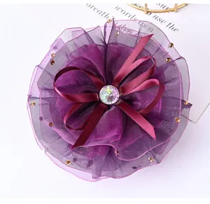 Close-up of a purple organza flower hair clip with sparkling rhinestone and ribbons.
