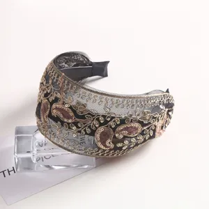 Exquisite gold embroidery on black mesh headband, detailed paisley texture, fine craft.