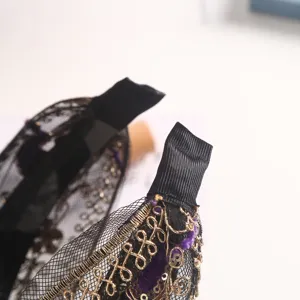 Detailed view of black mesh headband with gold embroidery, sequins and purple velvet accents.