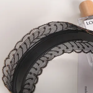 Close-up detail of the wide embroidered lace headband with inner teeth for anti-slip grip.